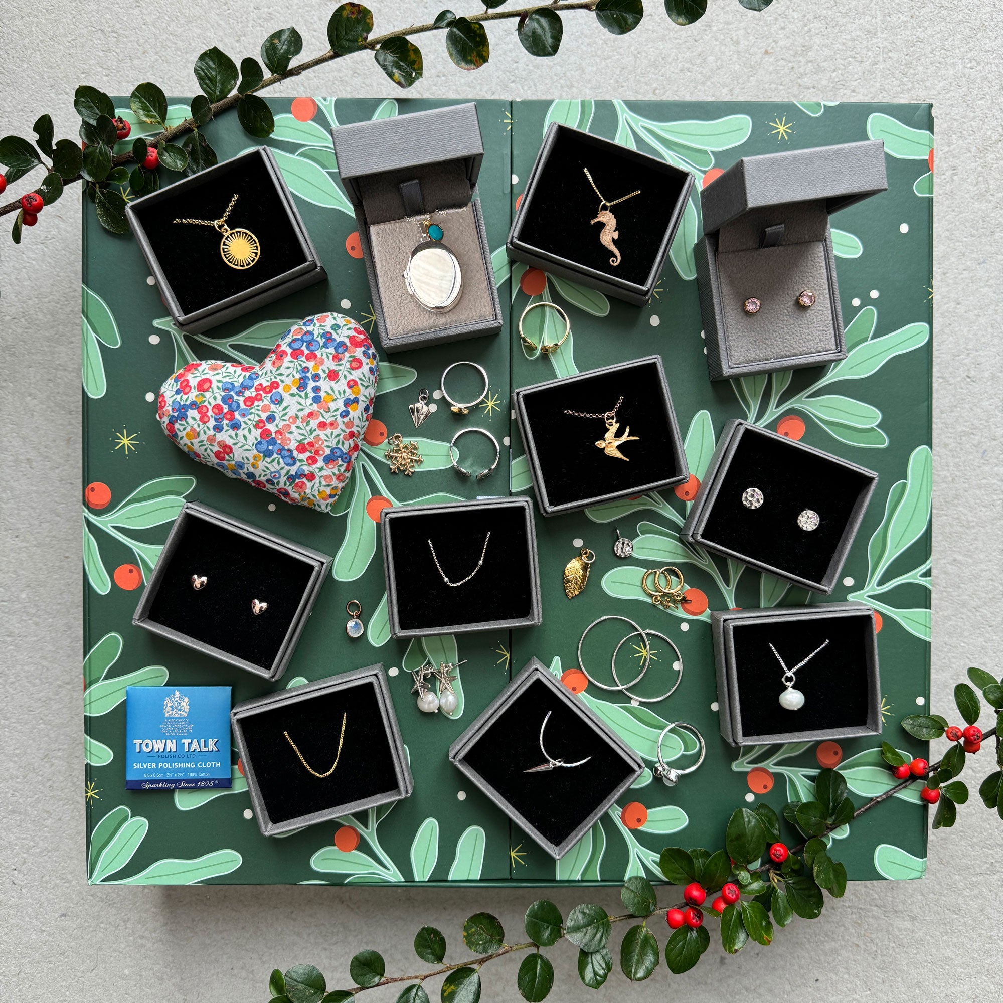 Jewelry set with various pieces displayed on a decorative green background with foliage.