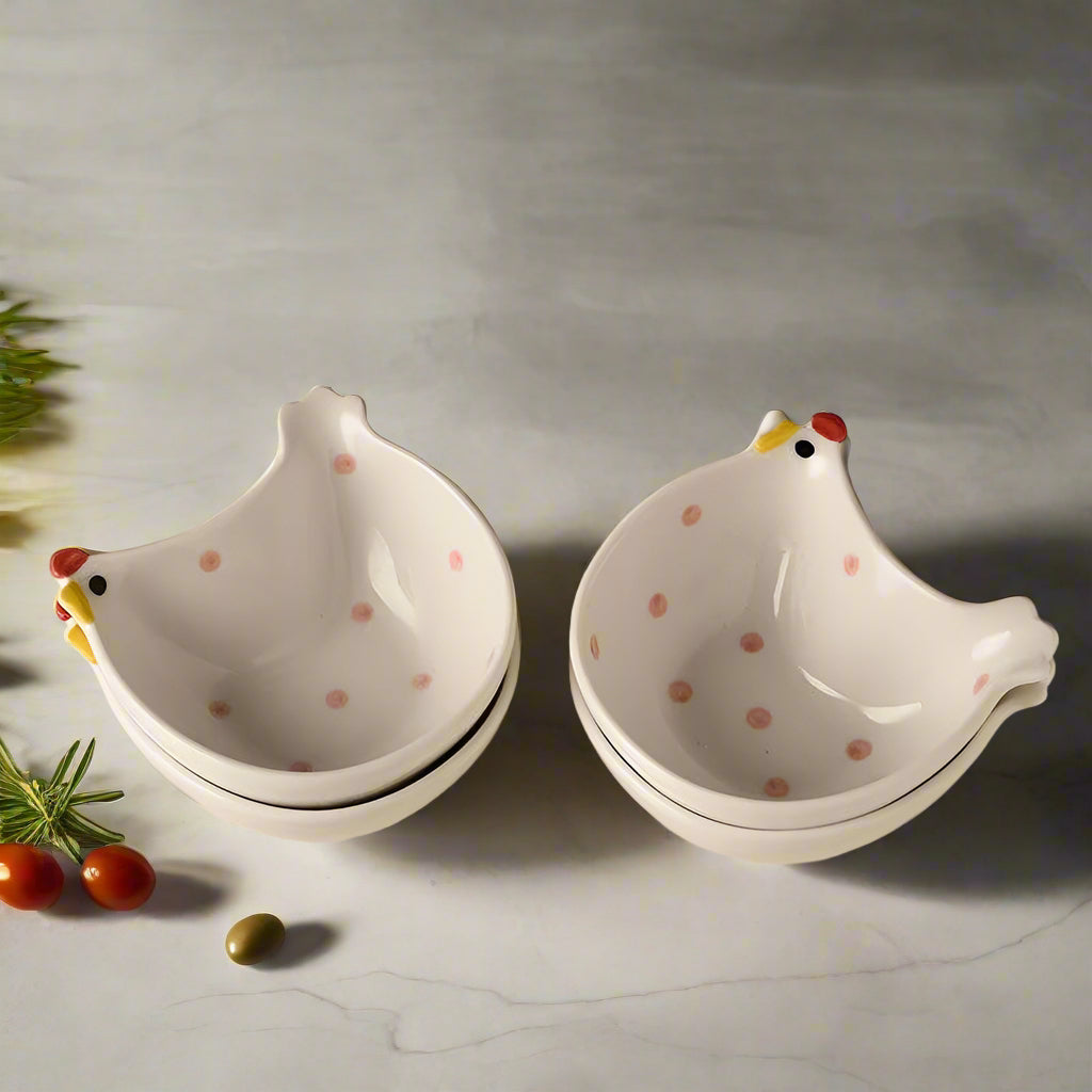 Two ceramic chicken-shaped bowls on a wooden surface