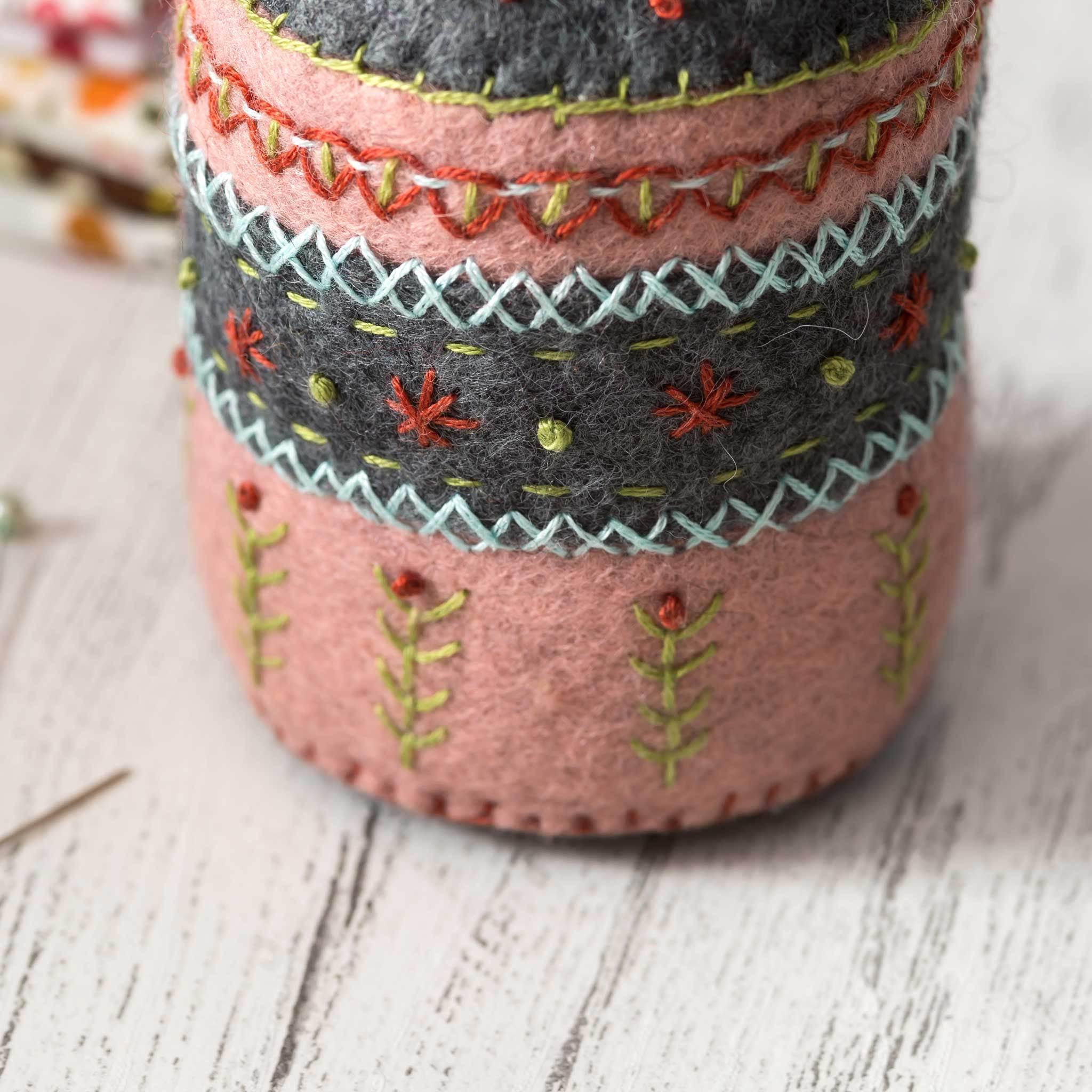 Decorative felt container with embroidered patterns on a wooden surface