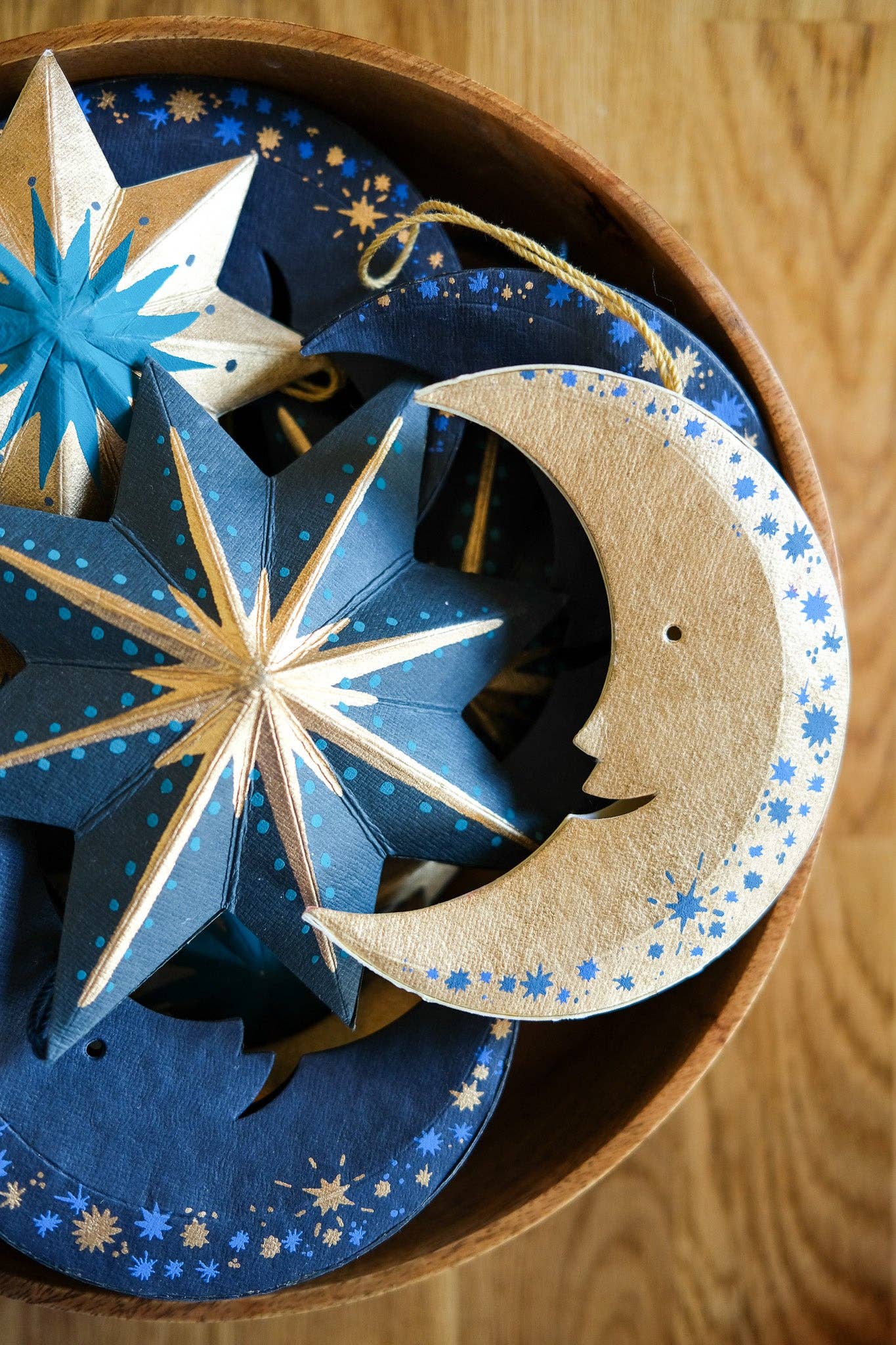 Decorative paper stars and moon with starry patterns in a box on a wooden surface