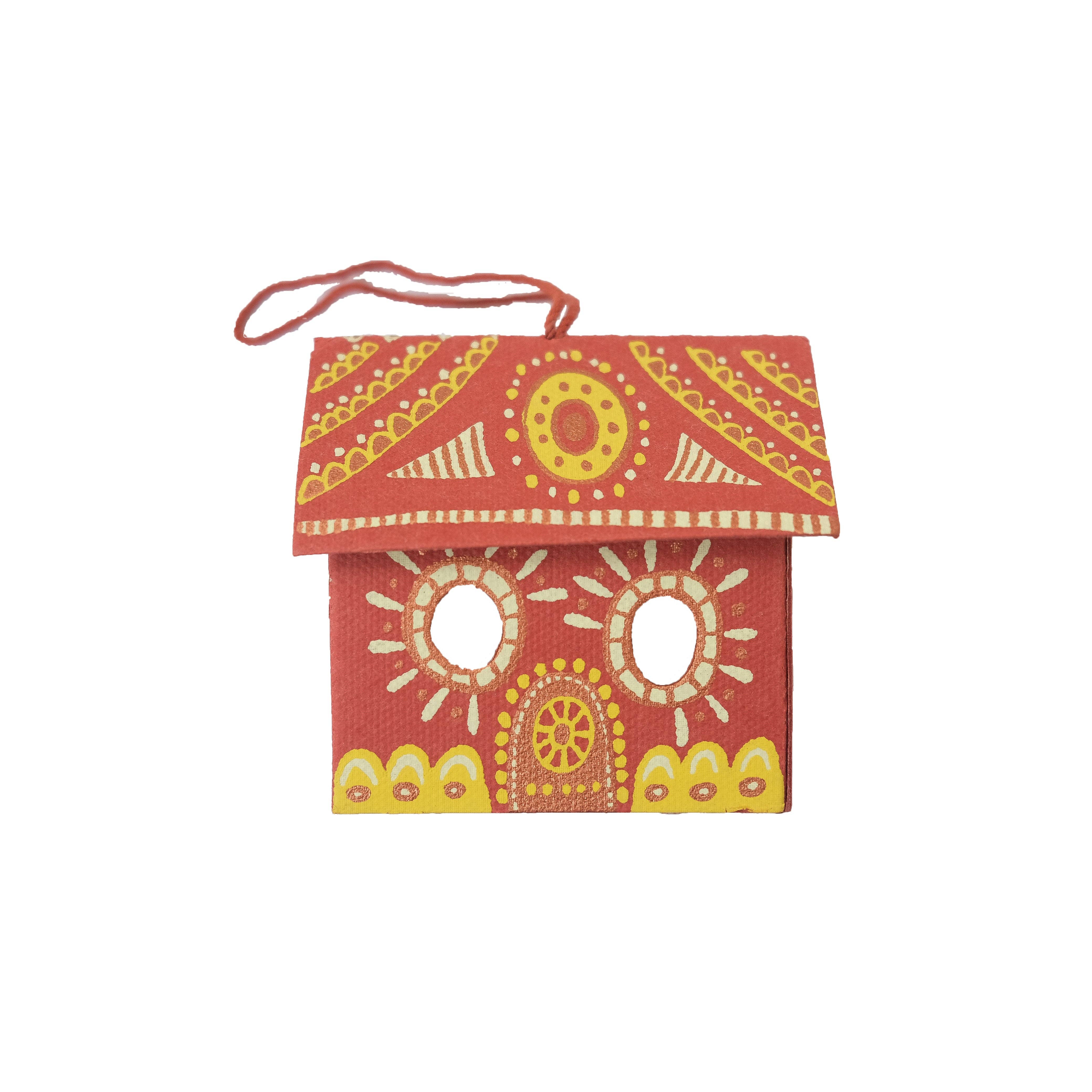 Decorative red birdhouse with yellow and white patterns on a white background