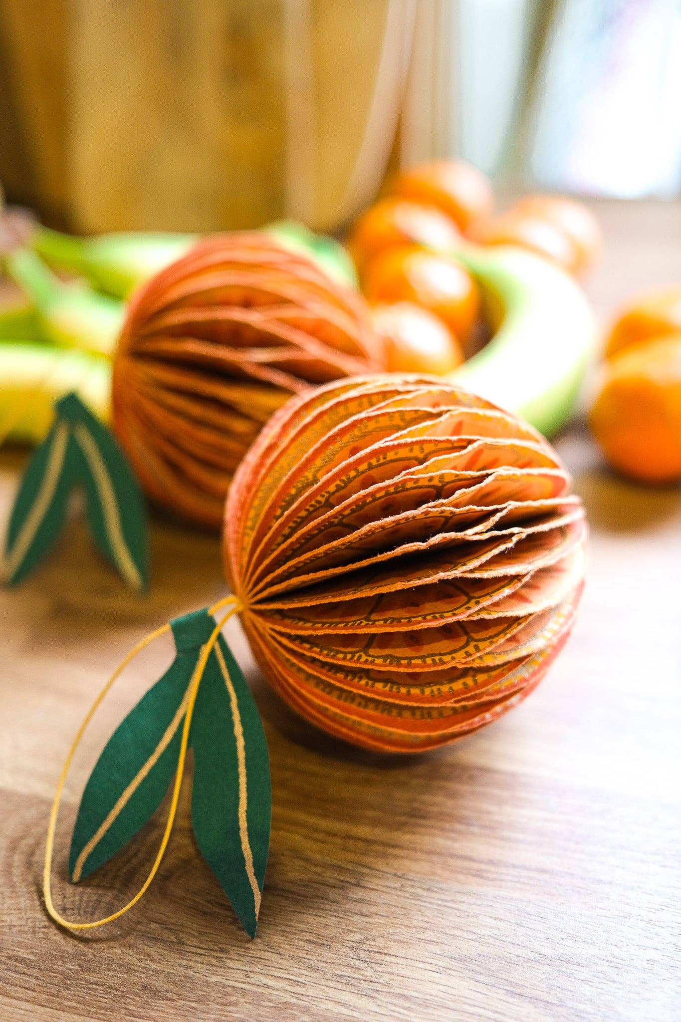 Decorative paper ball with green leaf accents on a wooden surface