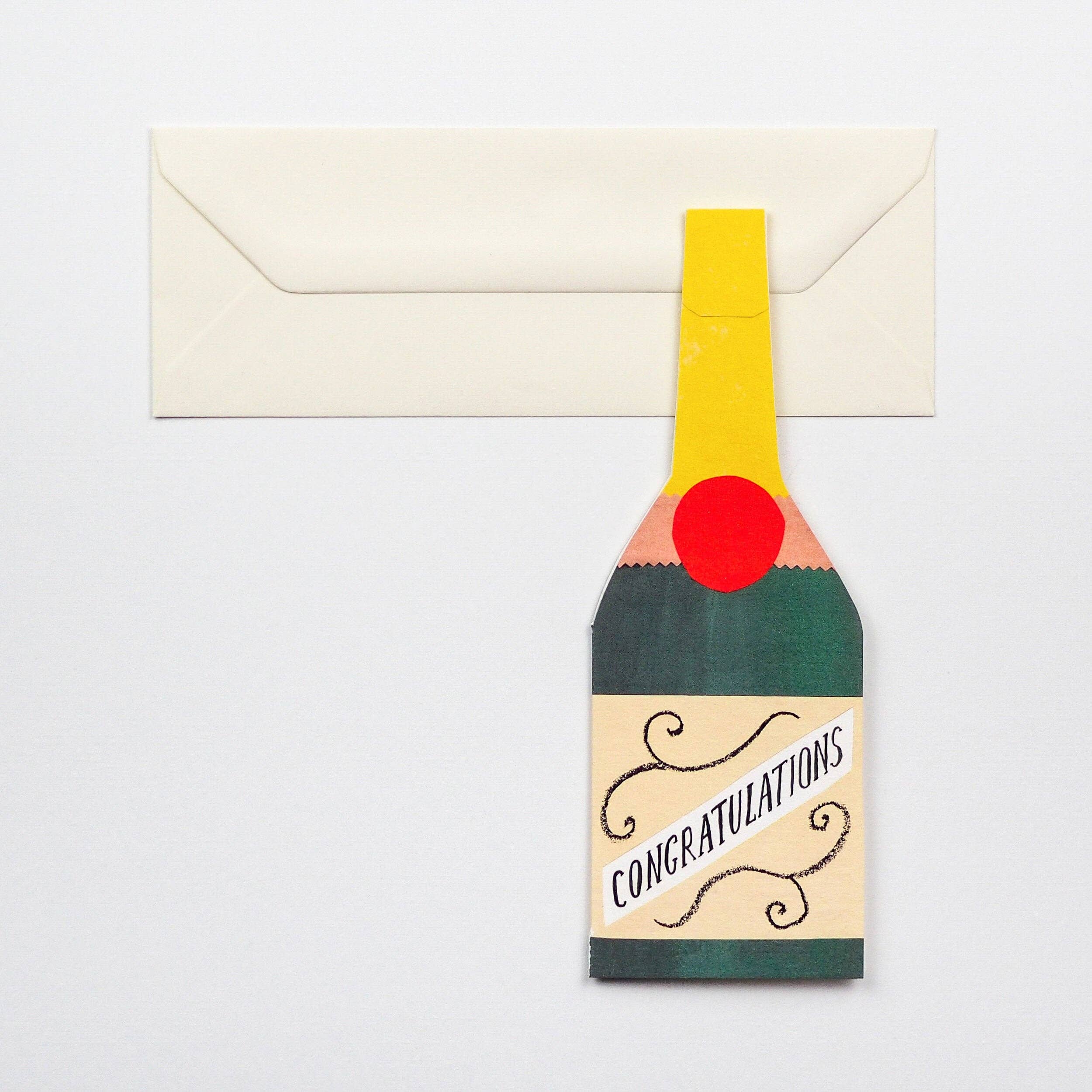 Greeting card designed like a champagne bottle with 'Congratulations' text, attached to an envelope.