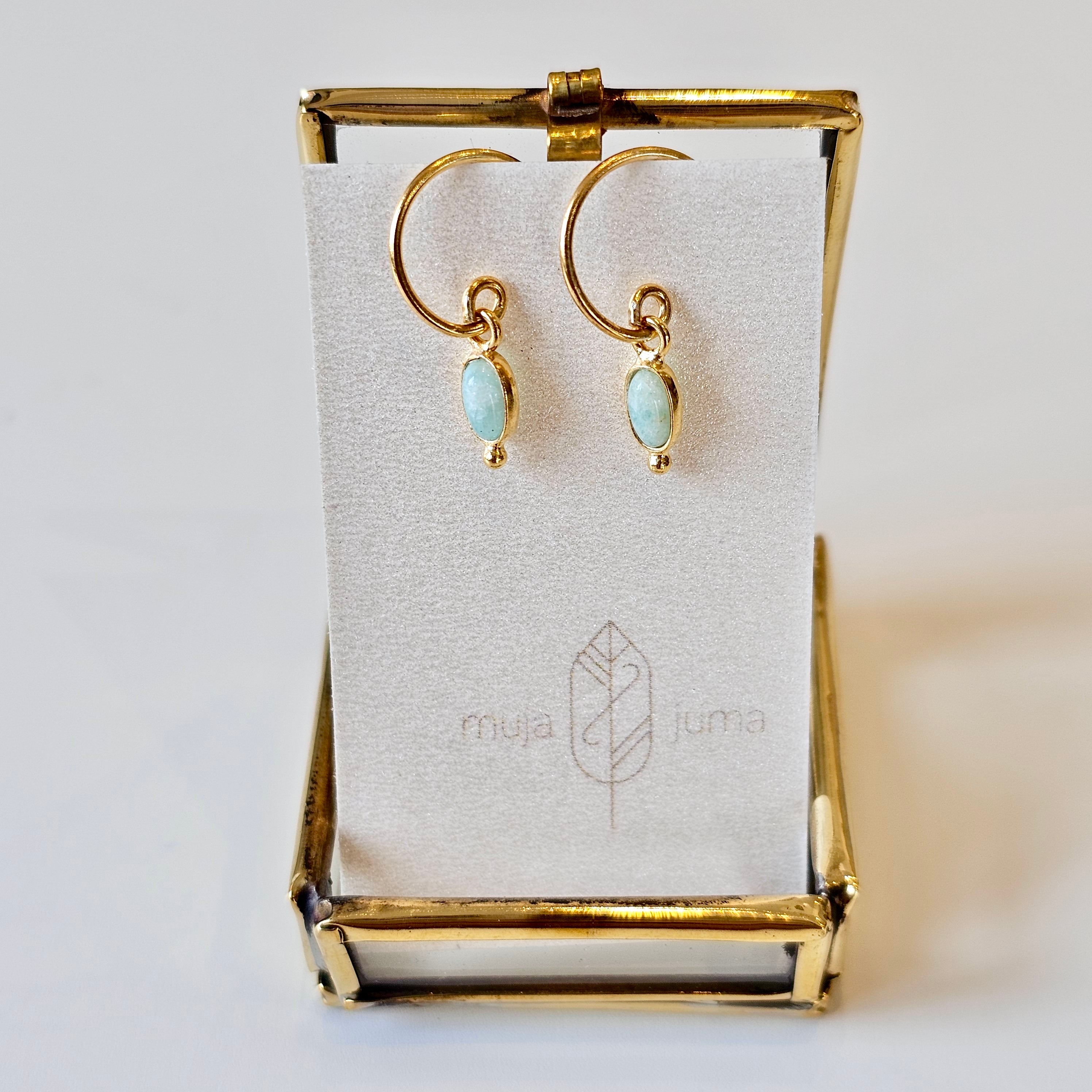 Gold earrings with light blue stones on a branded card