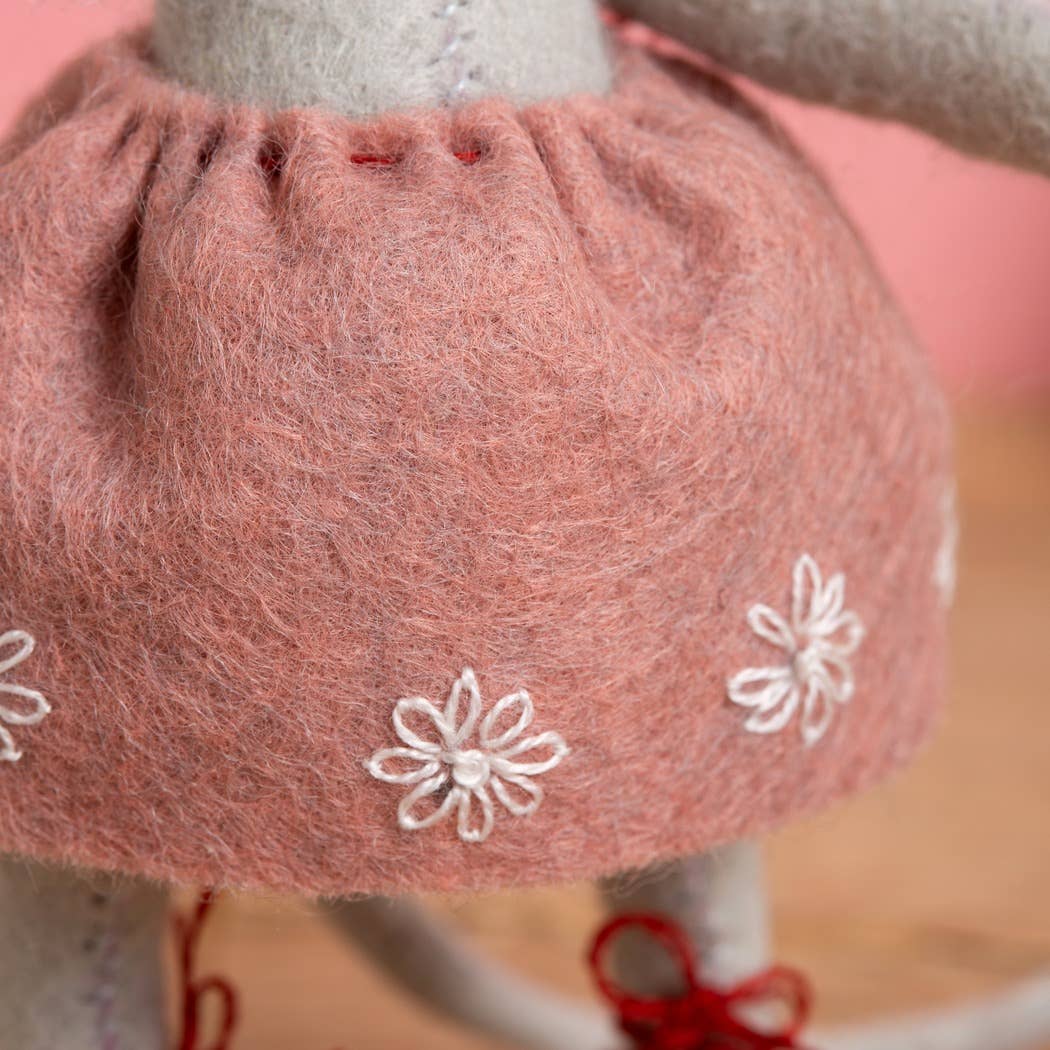 Close-up of a pink skirt with white floral embroidery on a blurred background