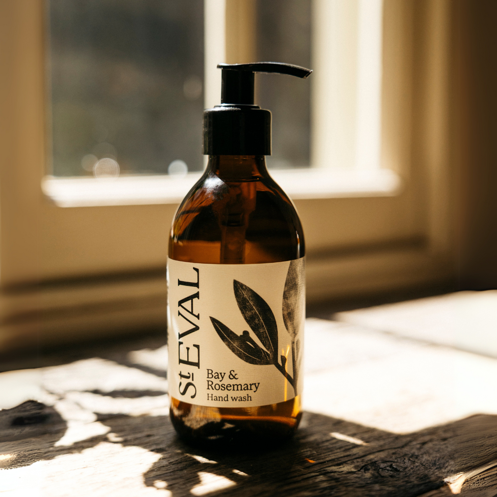 A bottle of St Eval Bay & Rosemary hand wash sitting on a wooden windowsill with sunlight coming through.
