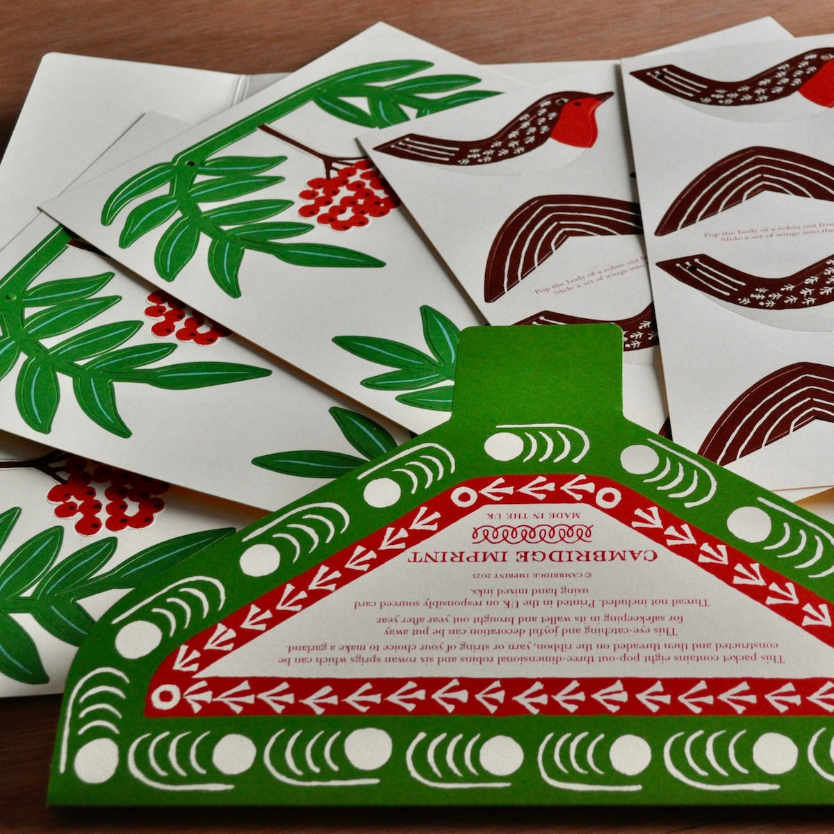 Set of Christmas-themed cards with green, red, and brown designs on a wooden surface.