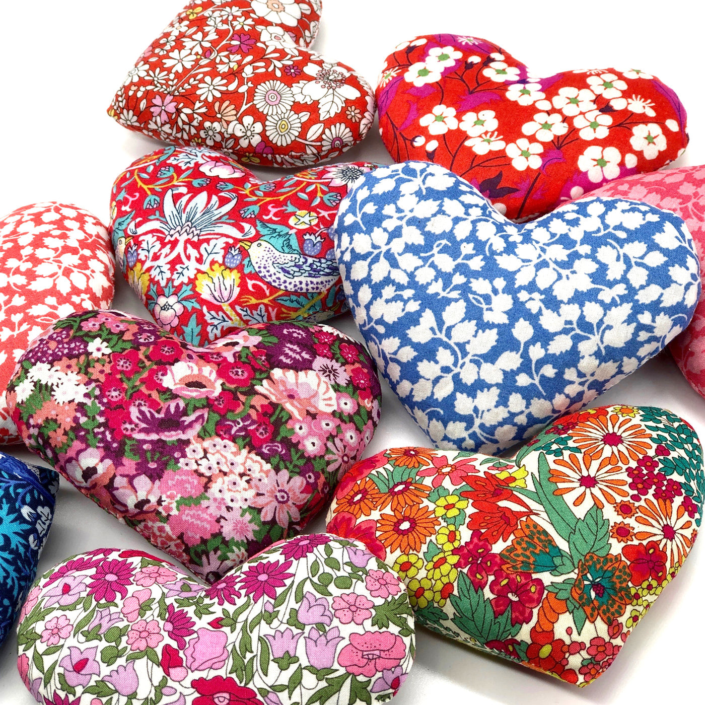 Heart-shaped fabric lavender cushions with colourful floral patterns on a white background