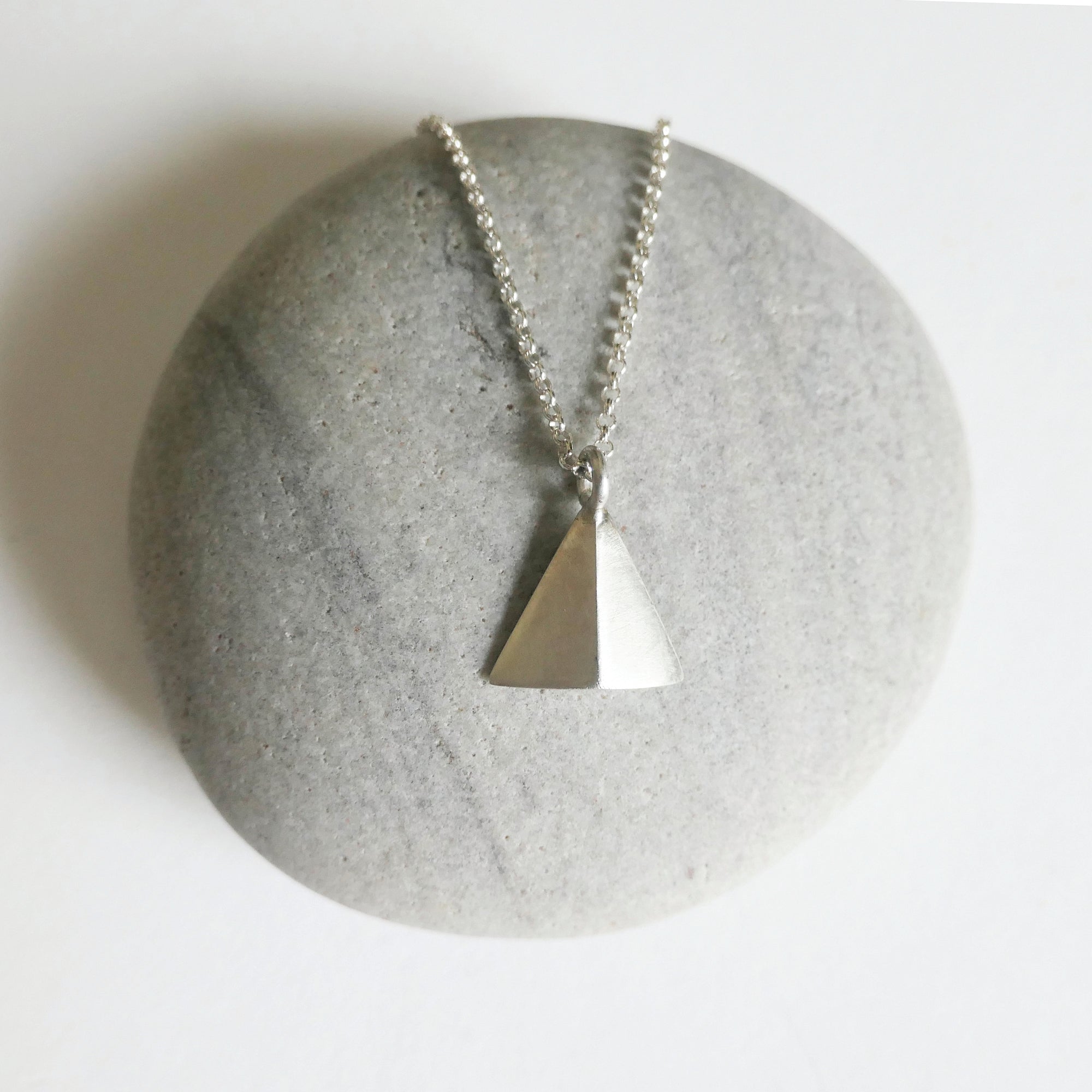 Necklace with a triangular pendant on a stone surface