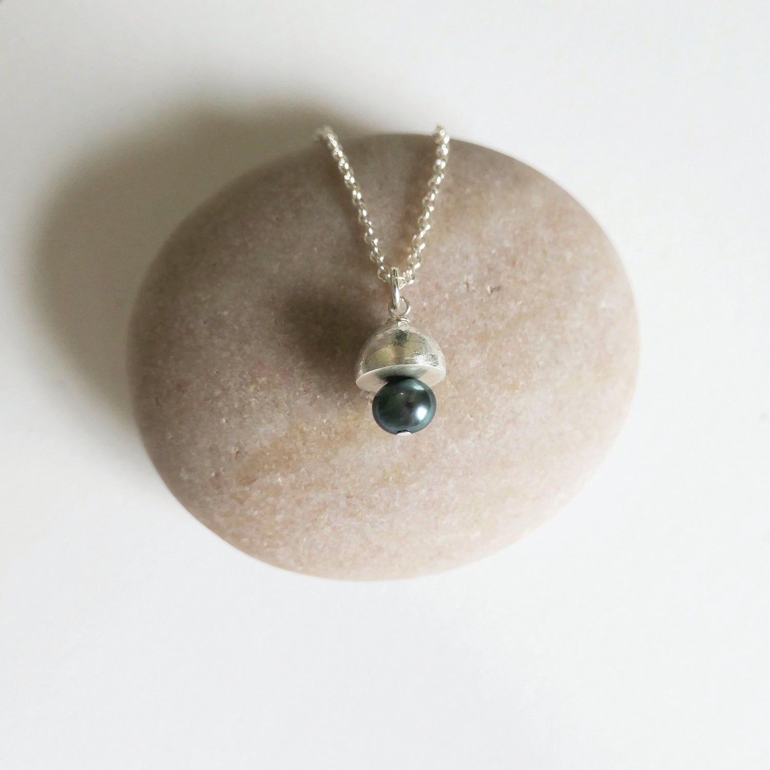 Necklace with a black pearl pendant on a stone surface
