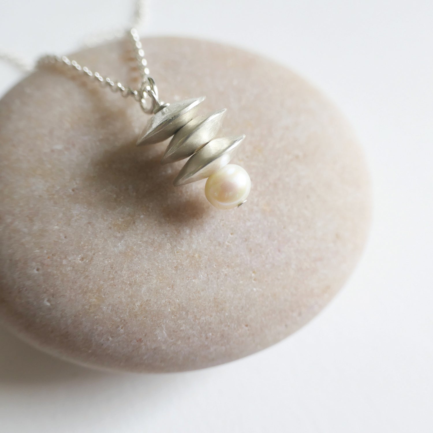 Necklace with a pearl pendant on a stone surface