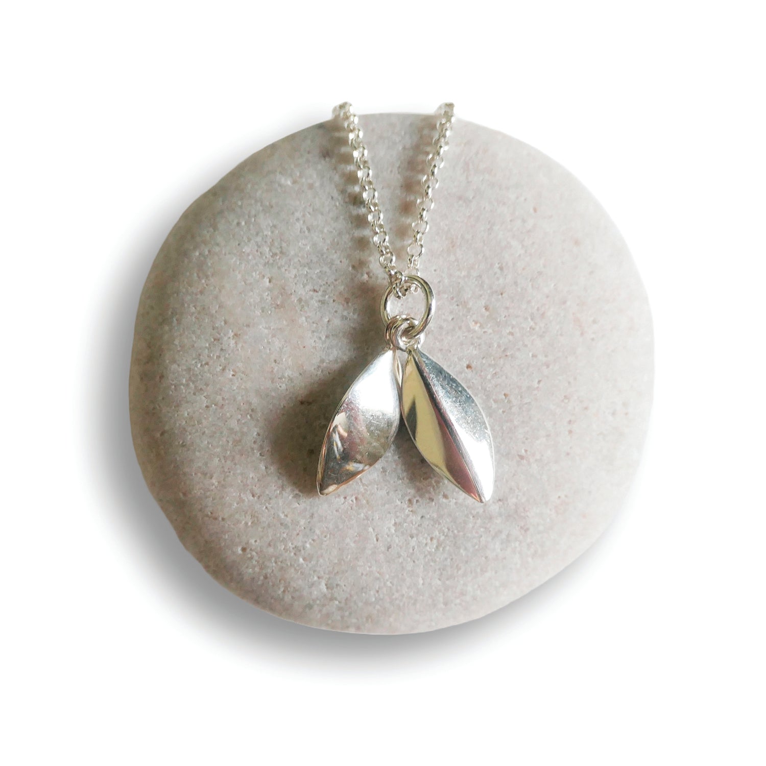 Silver necklace with leaf pendants on a round stone surface