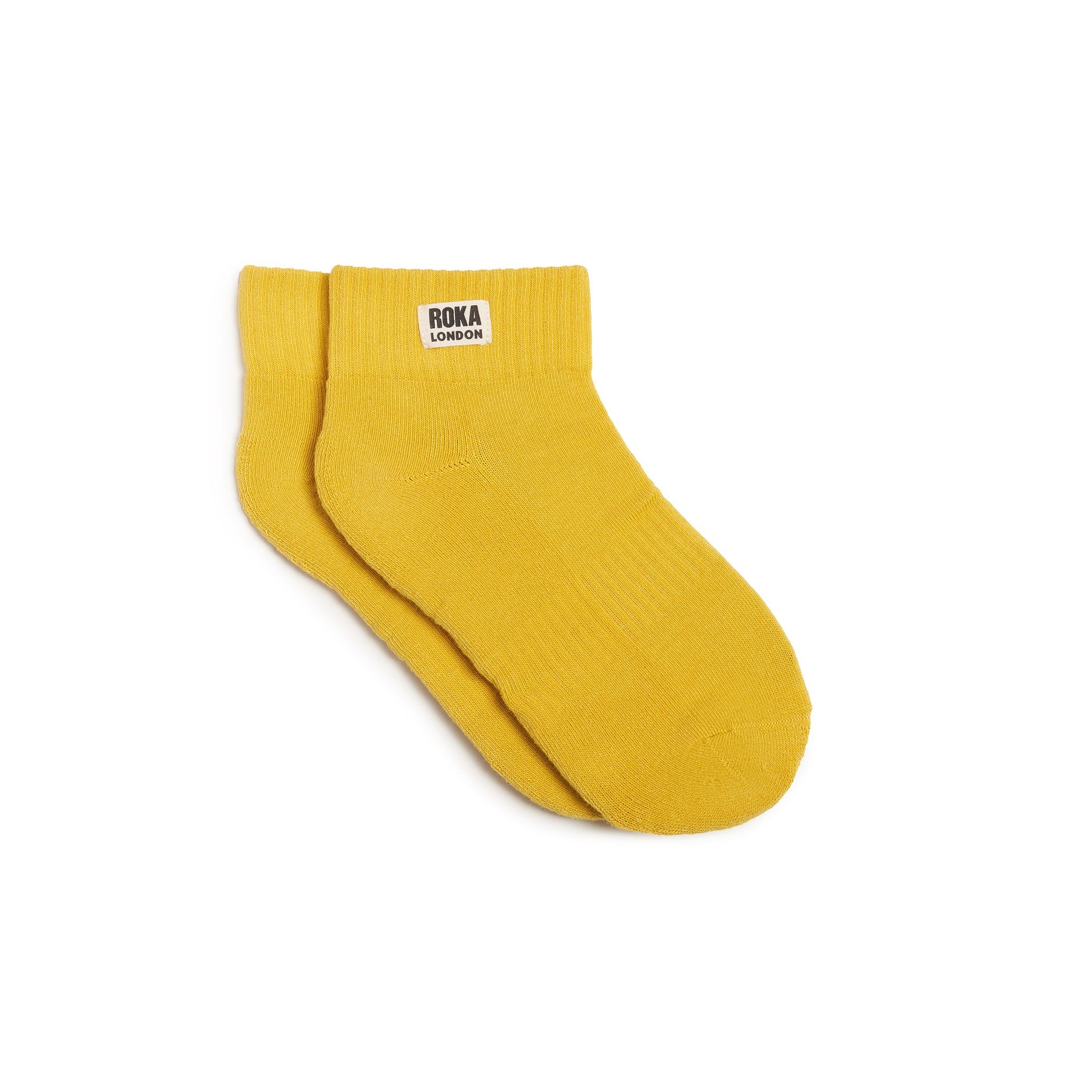 Yellow sock with Roka London label on a white background