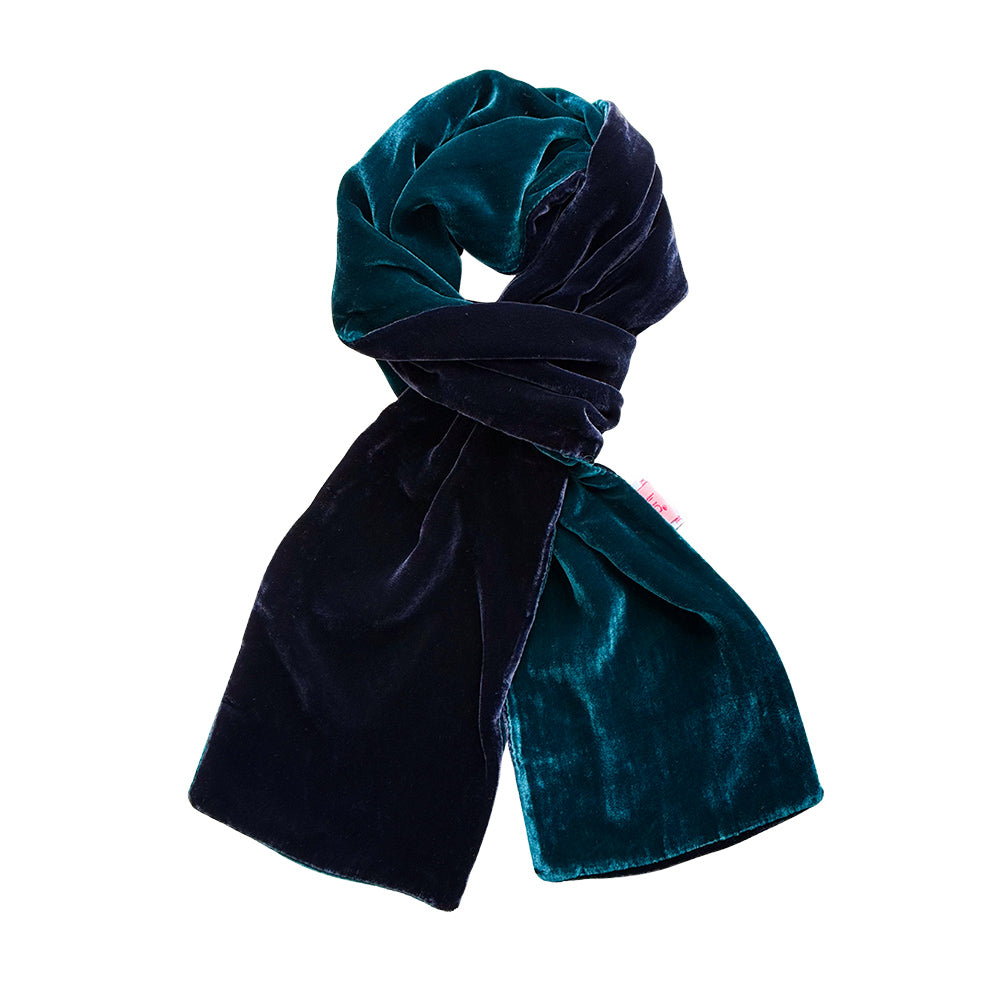A double-sided velvet scarf in deep teal and navy blue, styled in a loop on a solid white background.