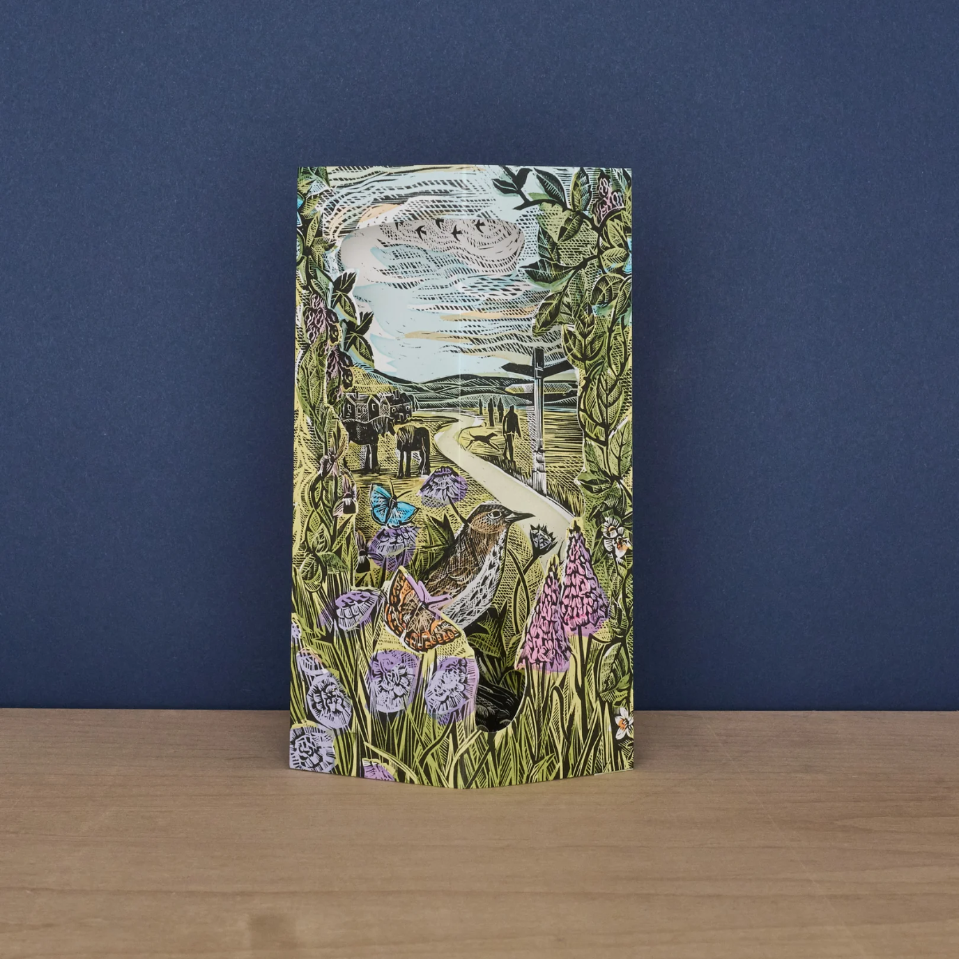 Decorative card with nature-themed design sat on a wooden surface against a blue background