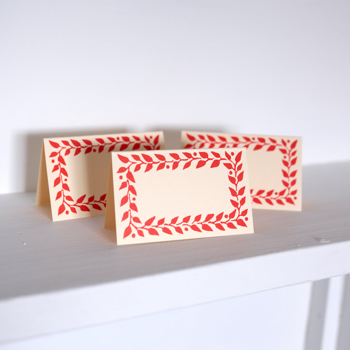 Three greeting cards with red leaf pattern on a white surface