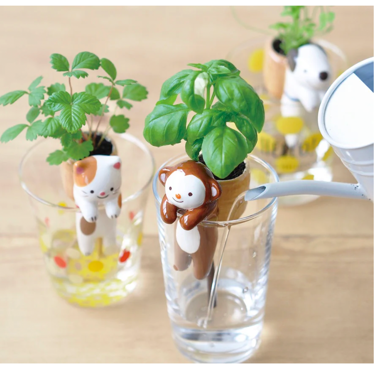Three small animal-shaped planters with green plants inside on a wooden surface.