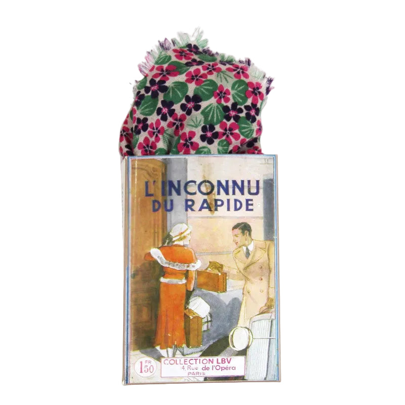 A folded floral scarf or handkerchief with pink, purple, green, and white flowers, partially pulled out of a vintage illustrated matchbox-style box labeled 'L'INCONNU DU RAPIDE' and 'COLLECTION LBV'.