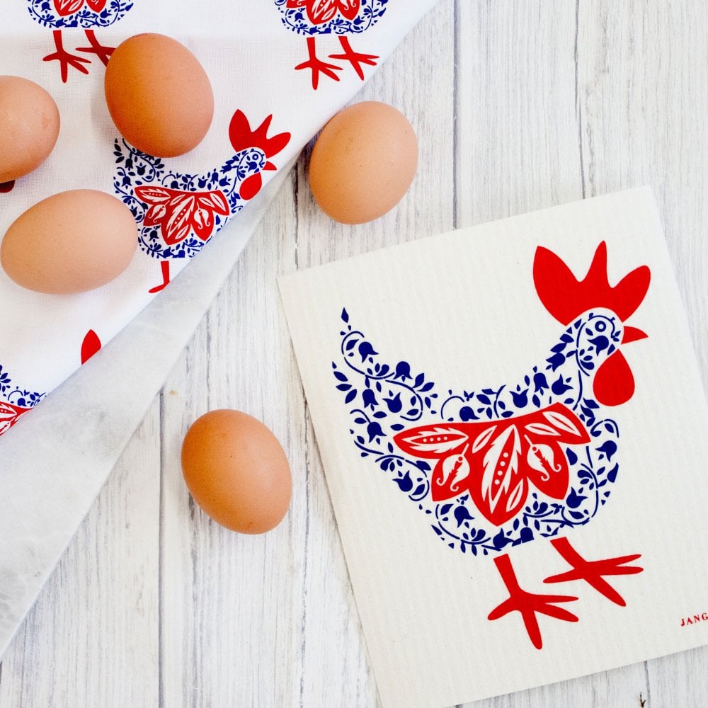 Eggs on a white surface with decorative towels featuring red and blue rooster designs.