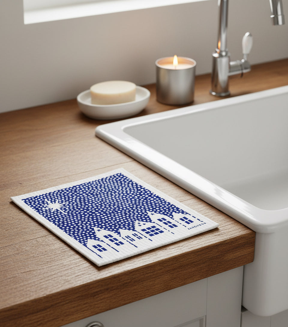 Blue and white swedish dishcloth on a wooden kitchen surface next to a belfast sink