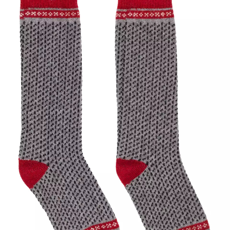 A pair of crew socks with a gray and red Nordic pattern, featuring solid red heels, toes, and cuffs, displayed against a plain white background.