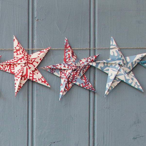 Decorative paper stars with red and blue patterns on a gray wooden background