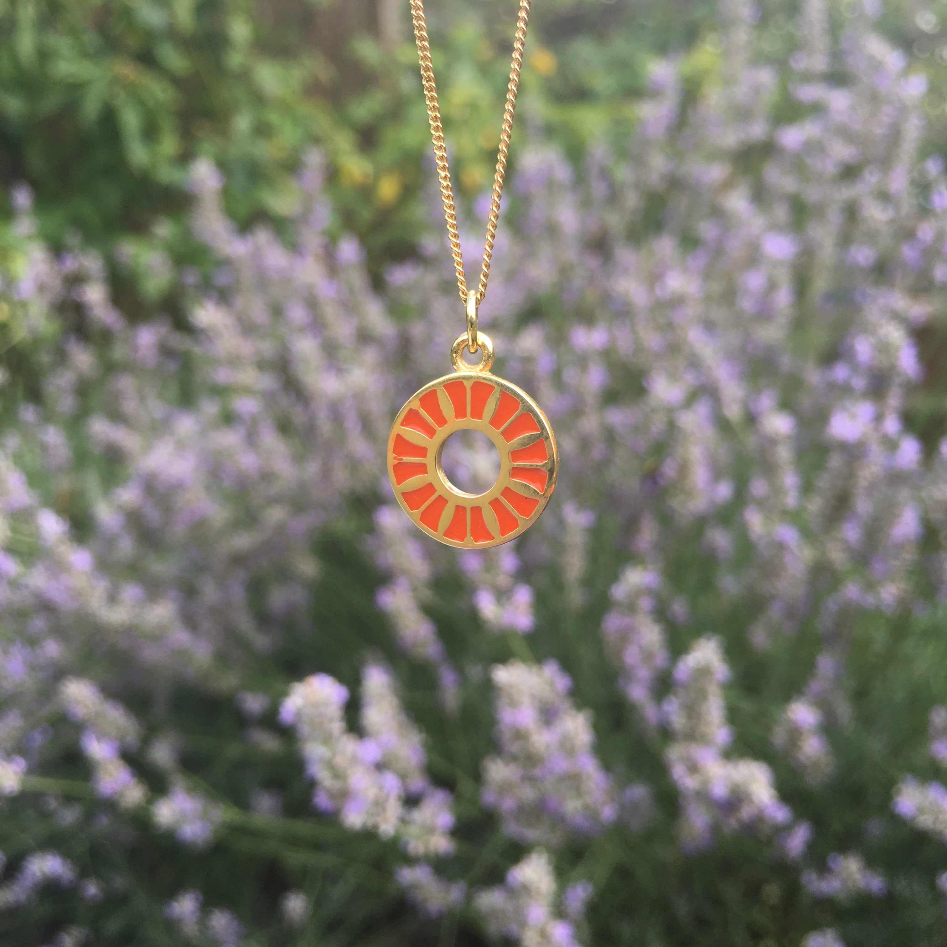 orange enamel flower ring in front of lavender