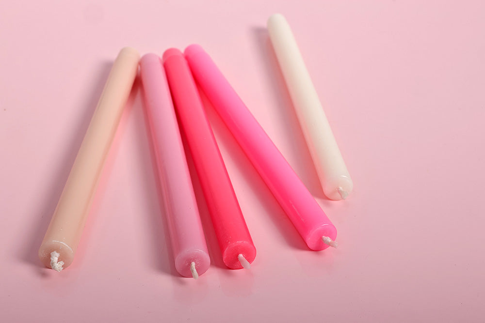 Set of pink and beige candles on a pink background