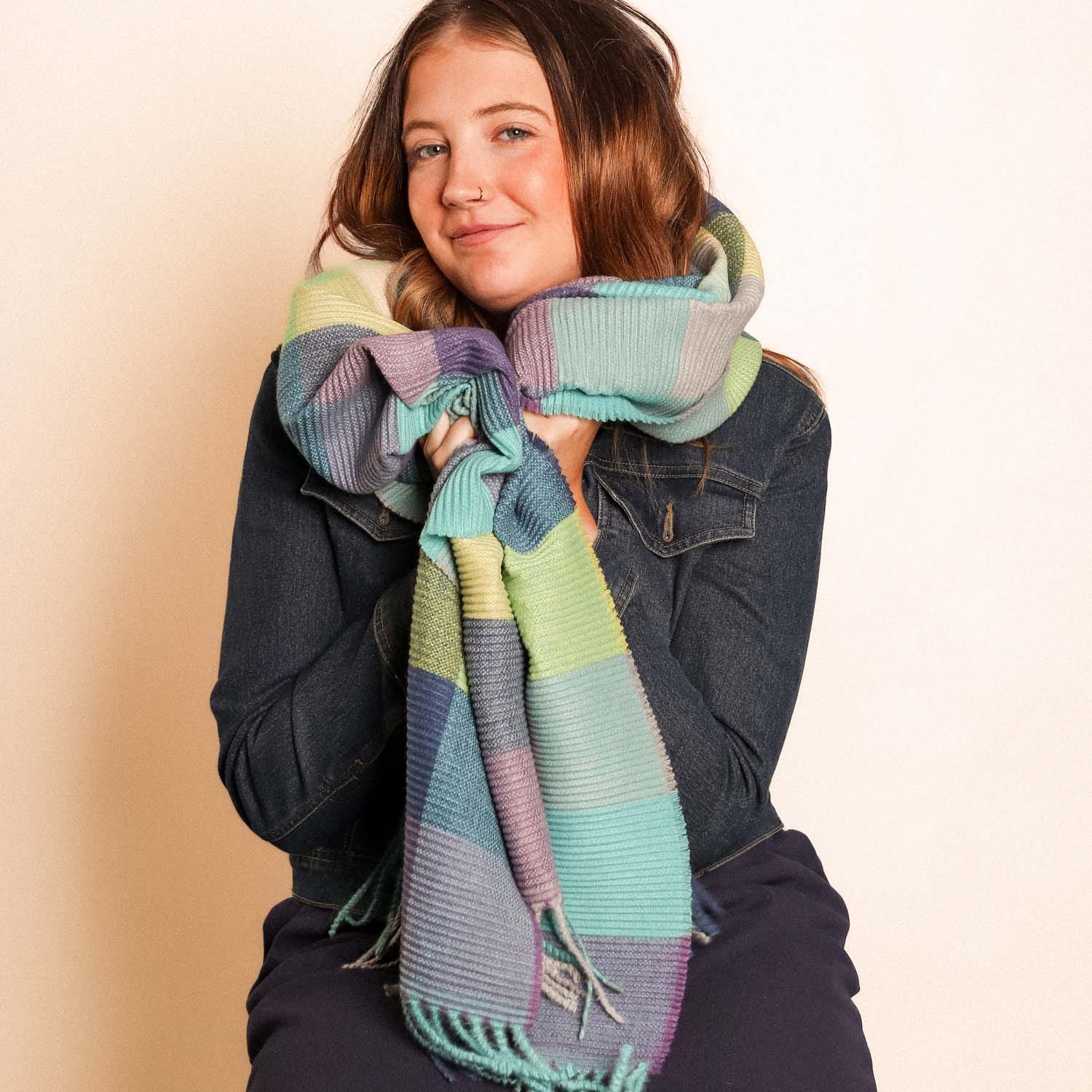 Woman wearing a colorful striped scarf against a beige background