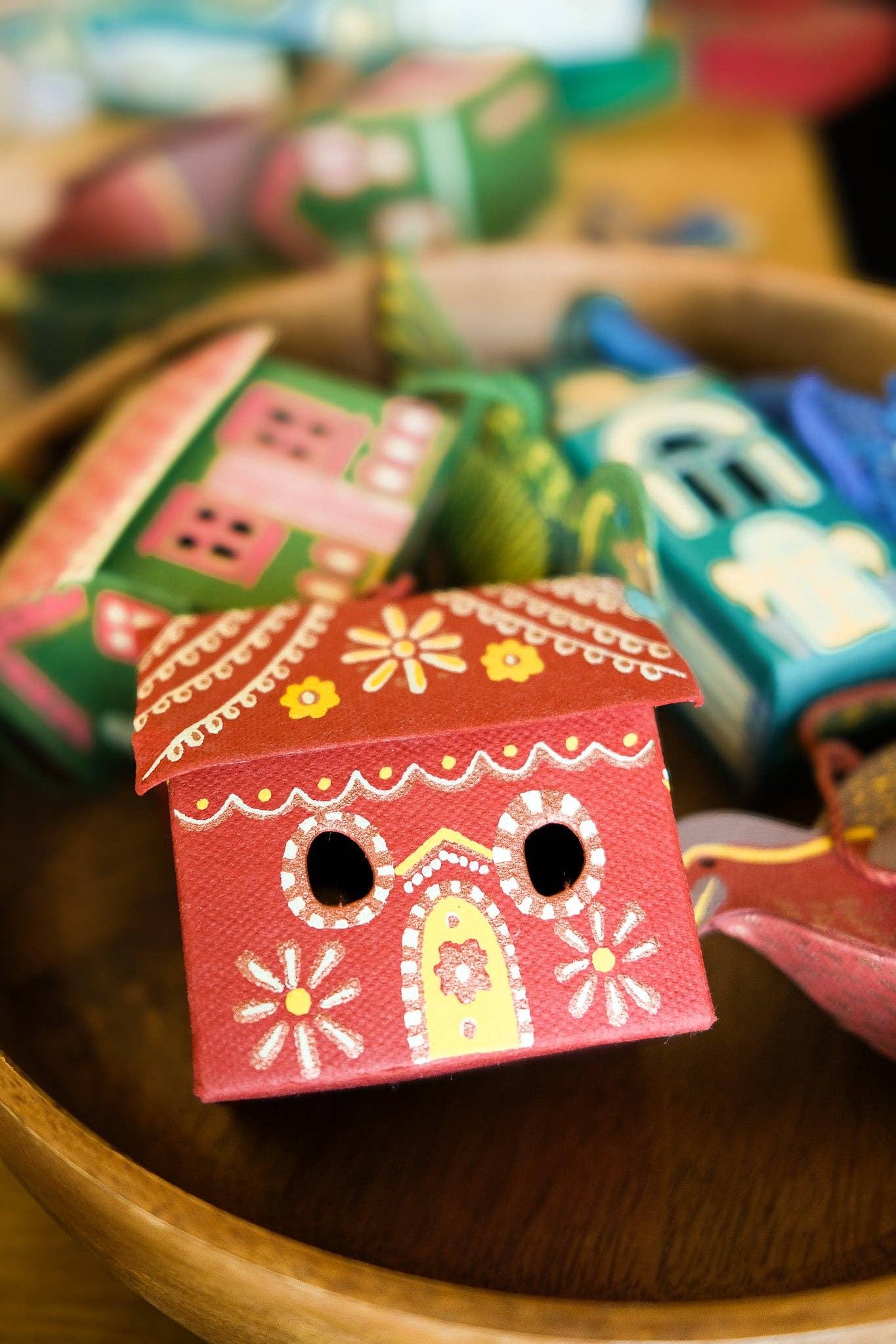 Colorful wooden house-shaped boxes with decorative patterns on a wooden surface.