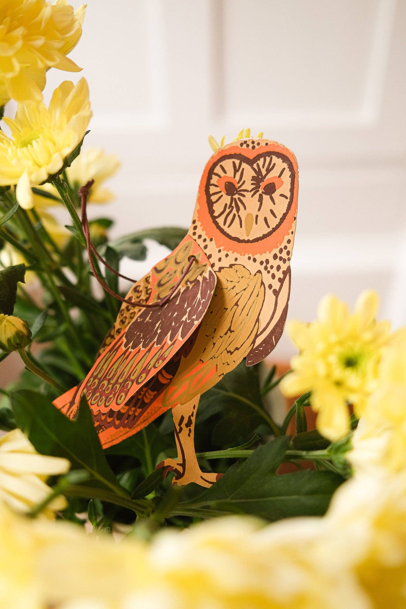 Decorative owl figurine among yellow flowers