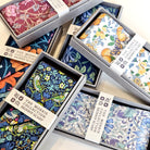Collection of patterned scarves in boxes with visible brand labels.
