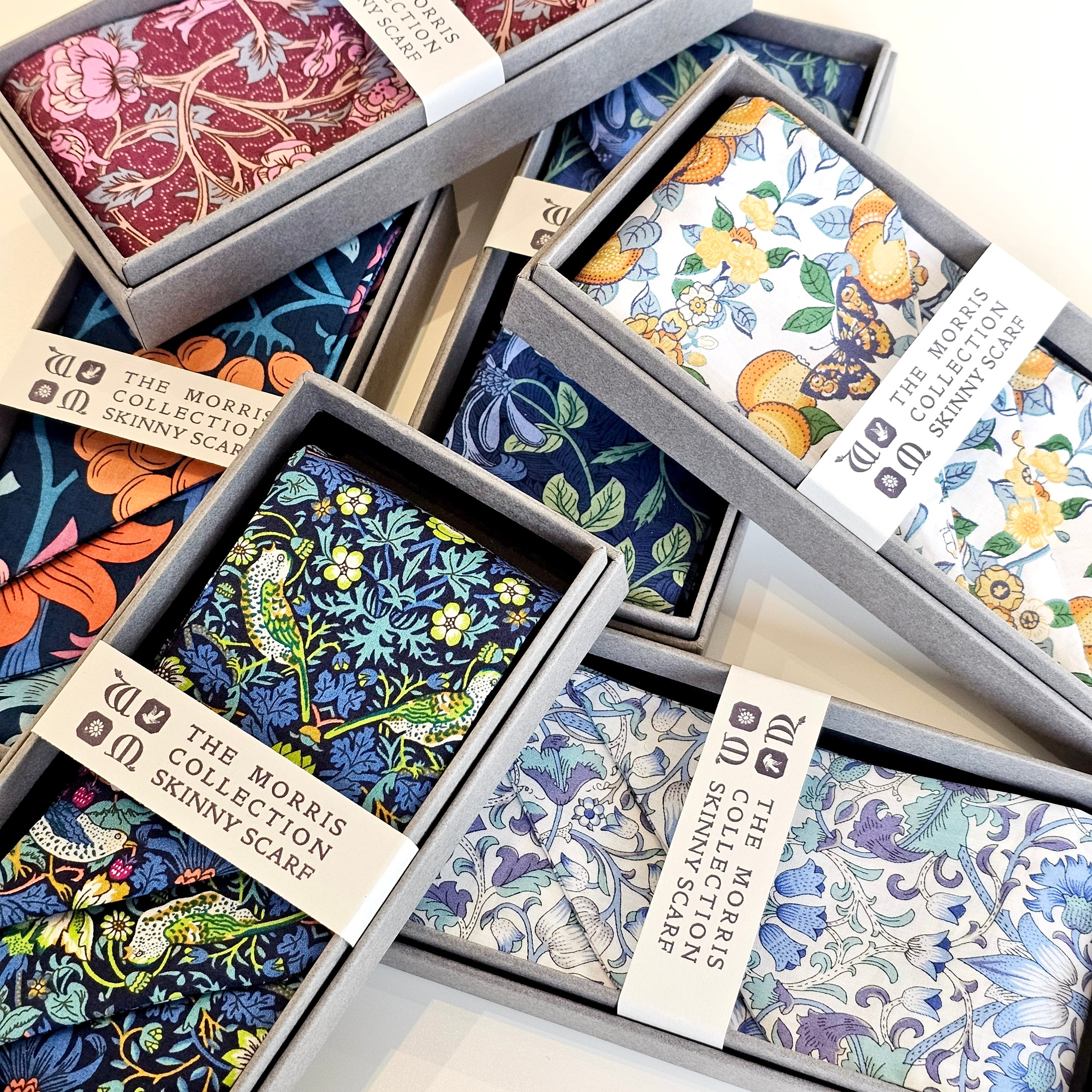 Collection of patterned scarves in boxes with visible brand labels.