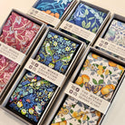 Collection of floral-patterned scarves in boxes with visible branding.