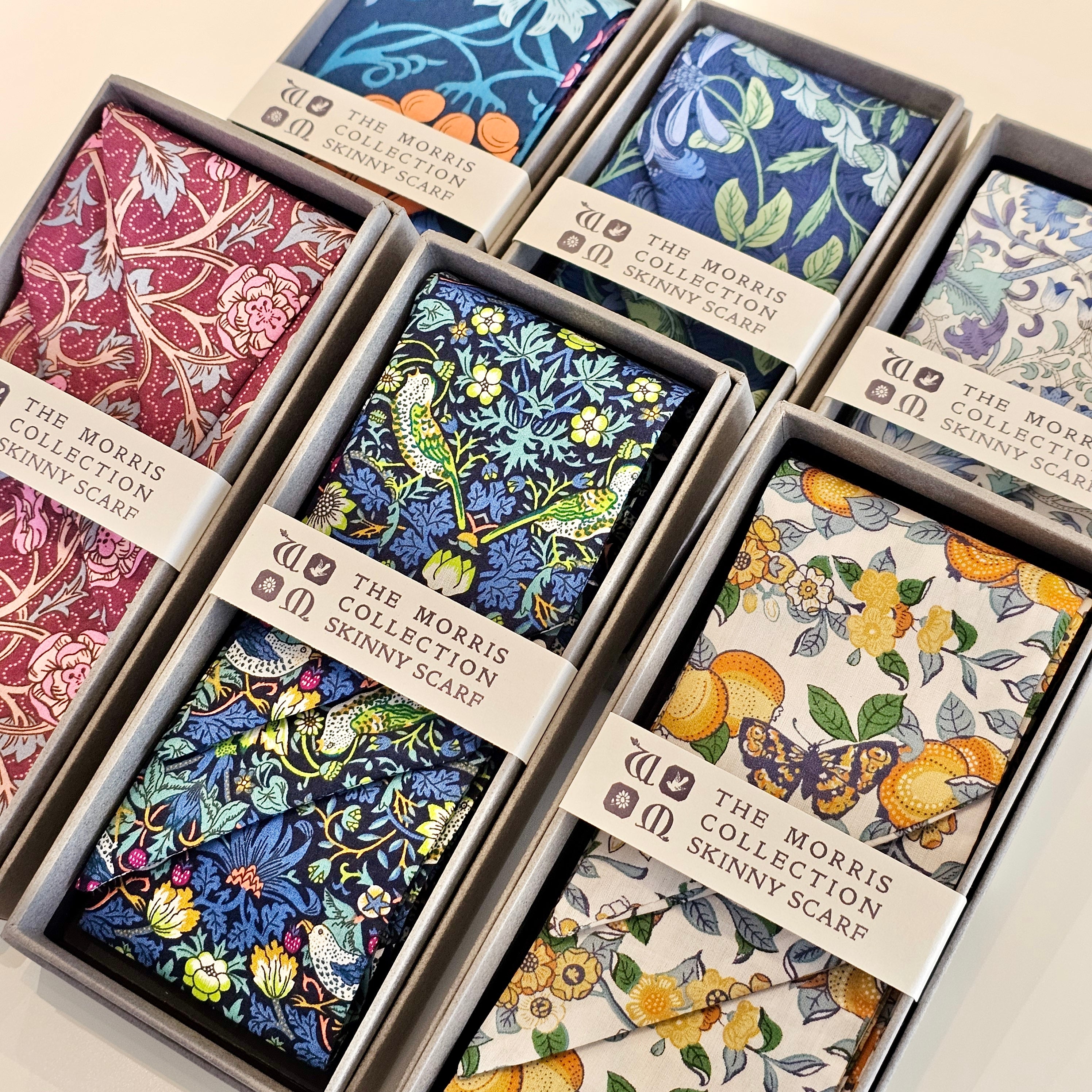 Collection of floral-patterned scarves in boxes with visible branding.