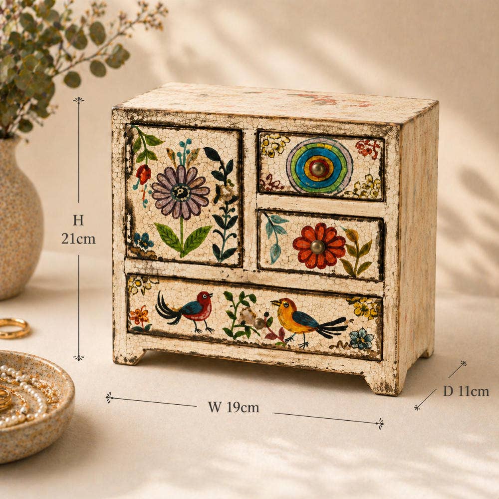 Small wooden dresser with floral and bird designs, placed on a light surface with a neutral background.