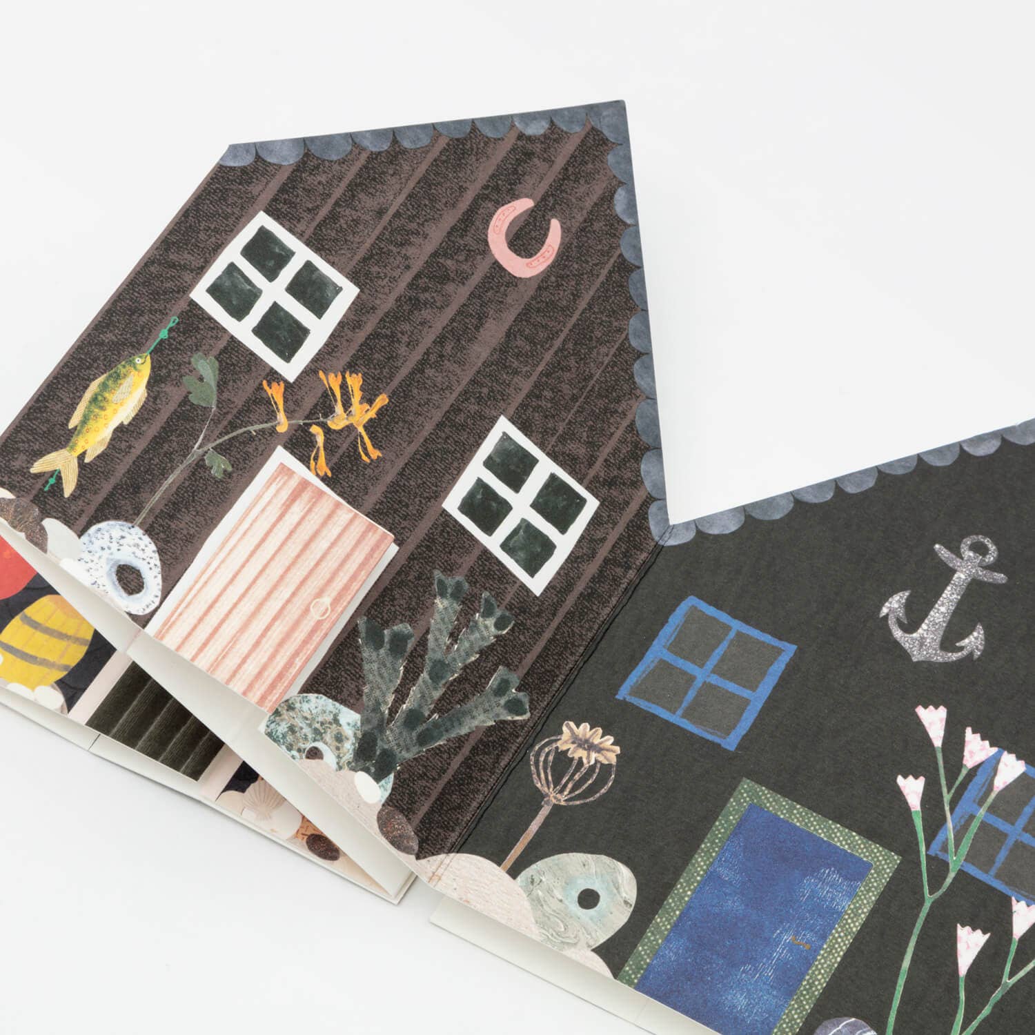 Illustrated house design on a notebook cover with various elements like windows, plants, and an anchor.
