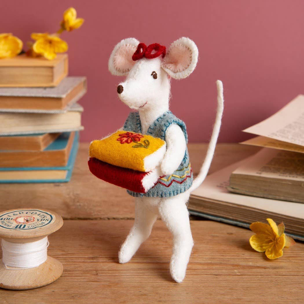 Stuffed mouse toy with a bow and books in the background