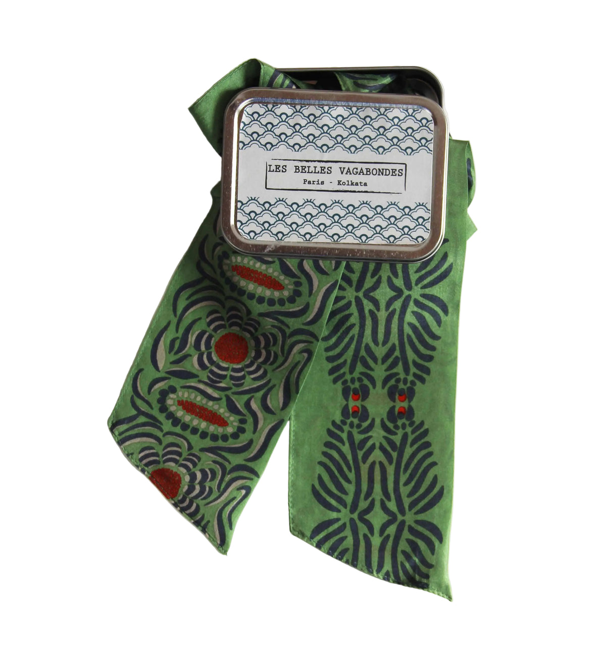 Green patterned ribbon with a small tin labeled 'Les Belles Vagabondes' on a white background