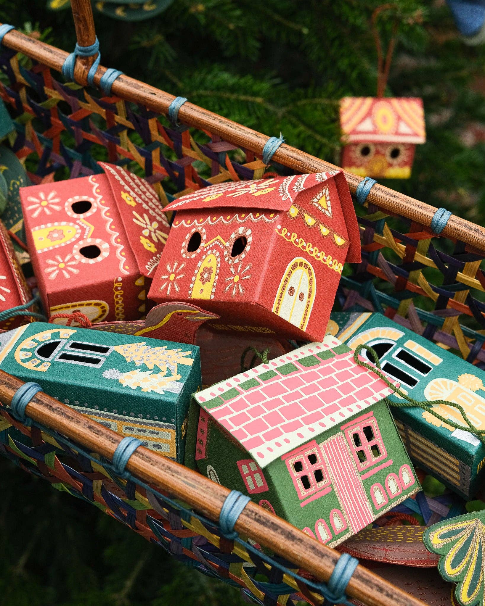 Colorful paper houses in a basket against a green leafy background