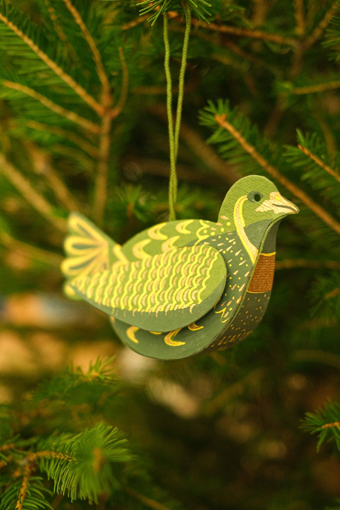 Decorative green bird ornament hanging on a Christmas tree.