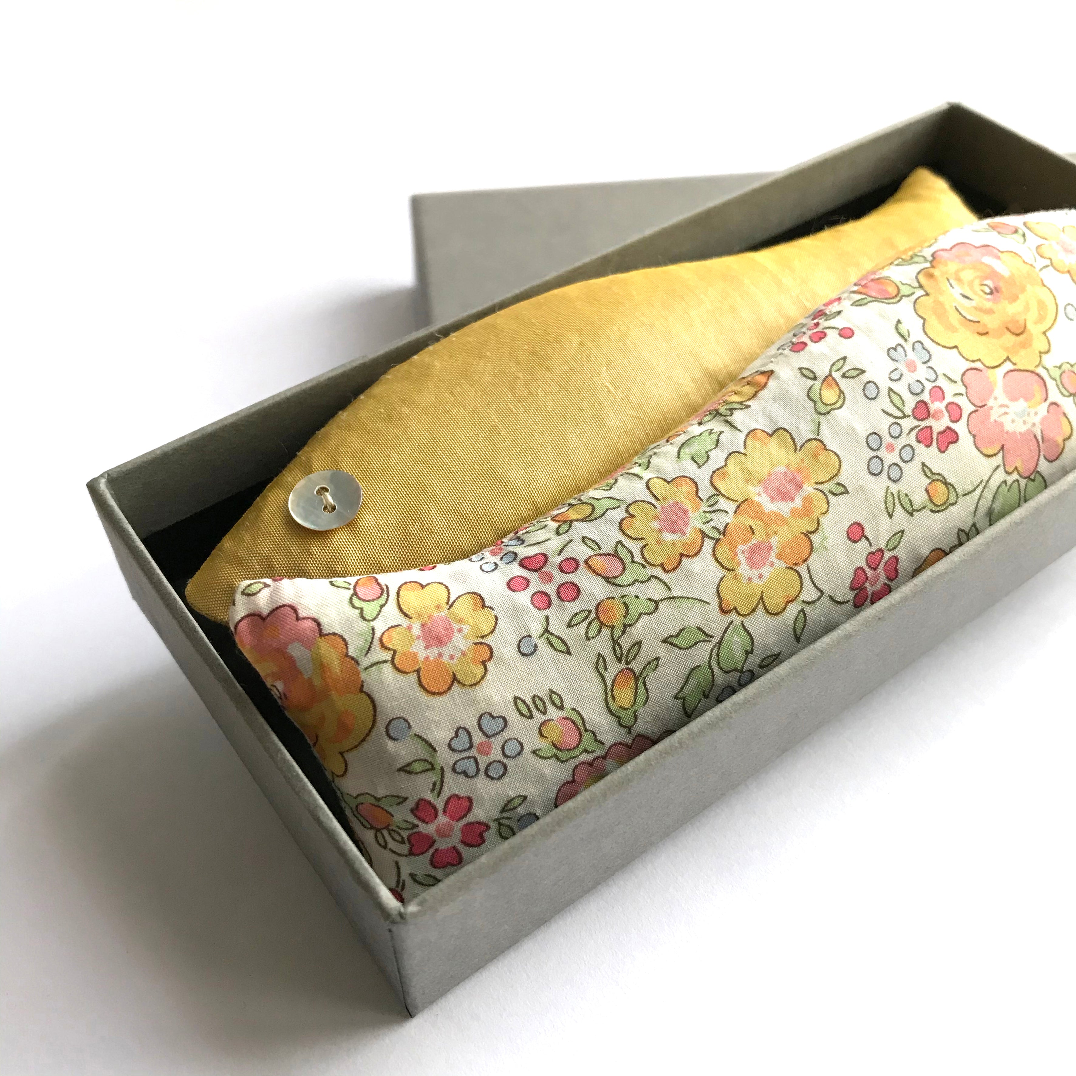 Two lavender cotton sachets in yellow in a box on a white background