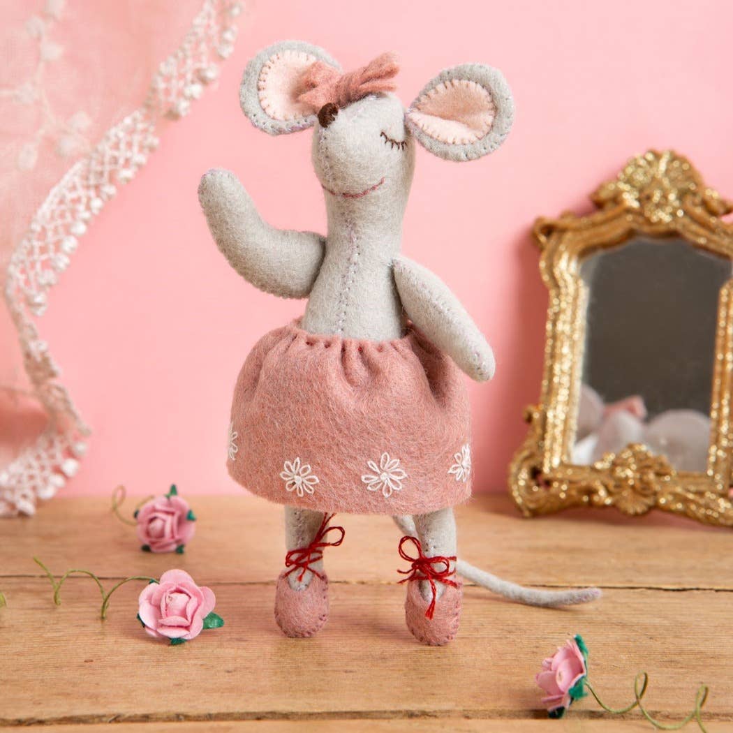 Toy mouse in a pink dress with flowers and a mirror on a wooden surface