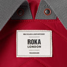 Close-up of a Roka London label on a red and gray fabric background