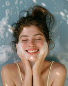Woman with soap suds on her face against a blue background