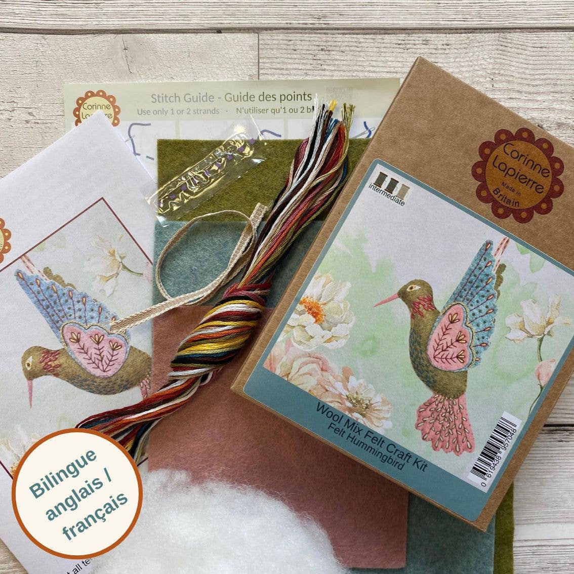 Craft kit with felt pieces, thread, and a guide on a wooden surface