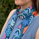 Person wearing a floral-patterned scarf with a blurred green background
