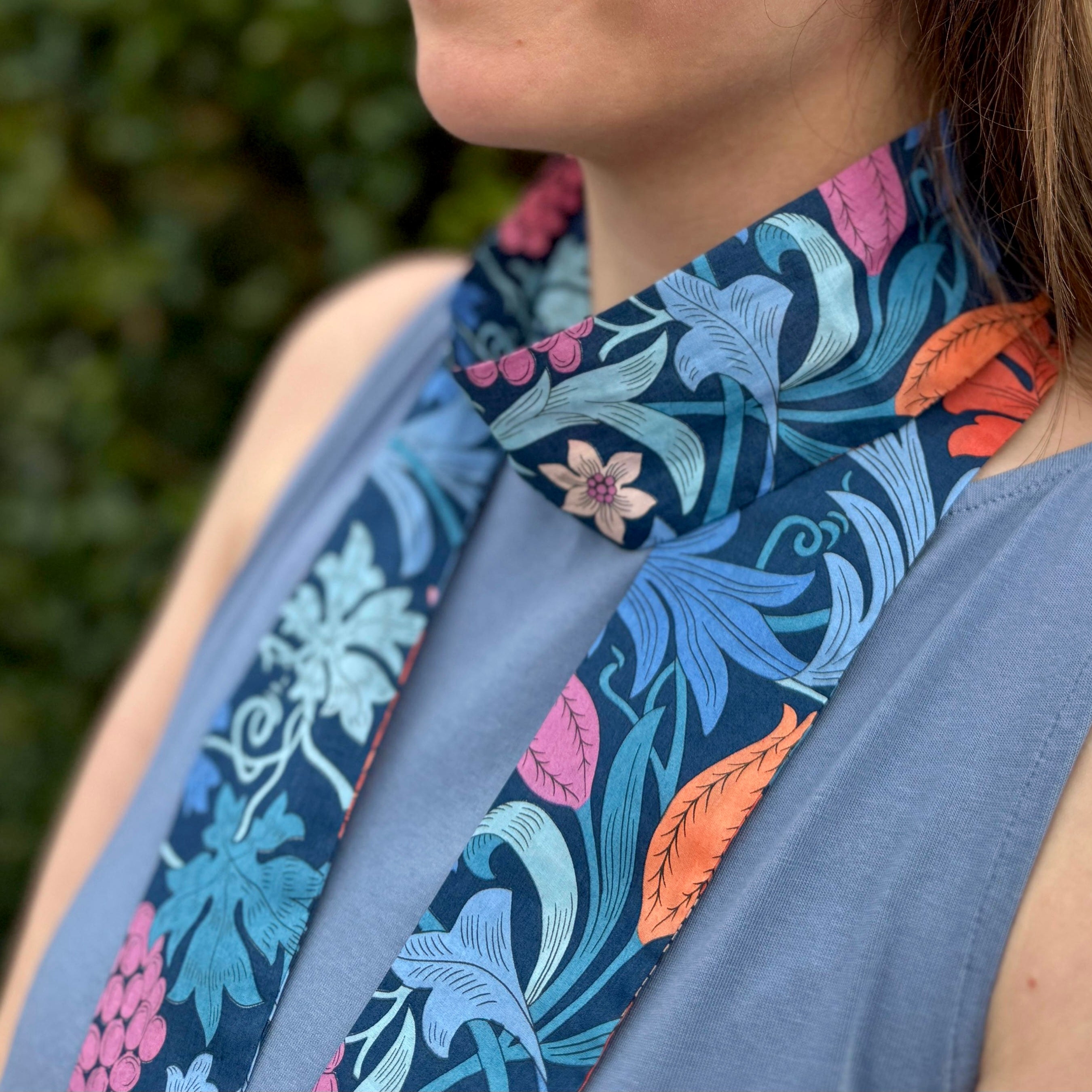 Person wearing a floral-patterned scarf with a blurred green background