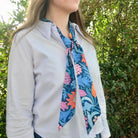 Person wearing a floral scarf with a green leafy background