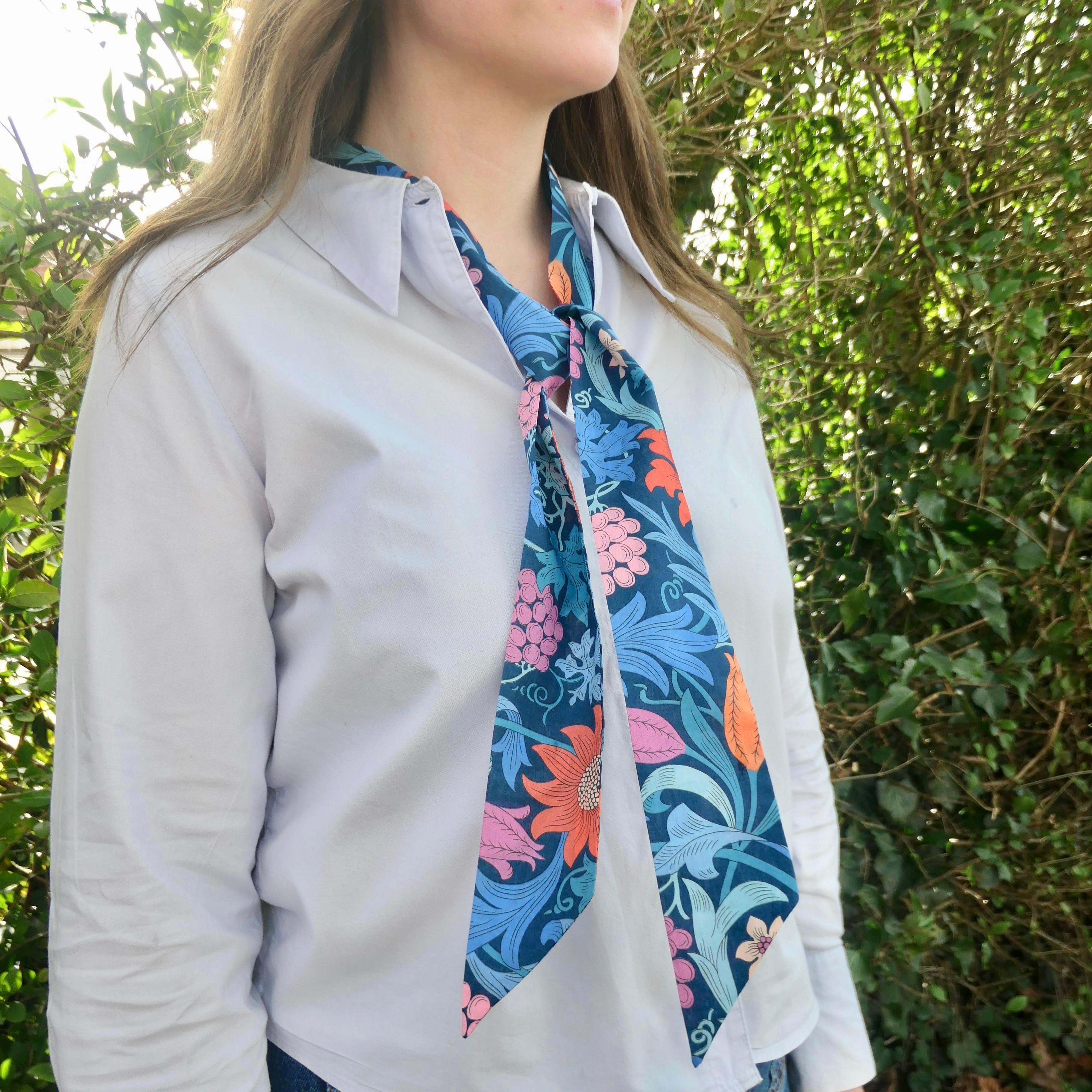 Person wearing a floral scarf with a green leafy background